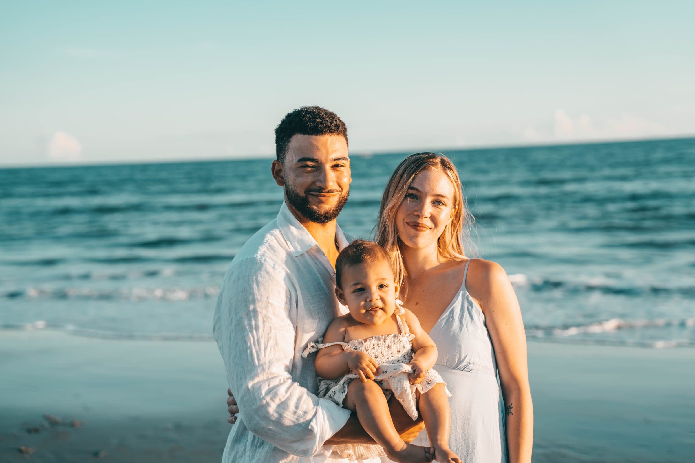 Young couple holding their baby girl by the water