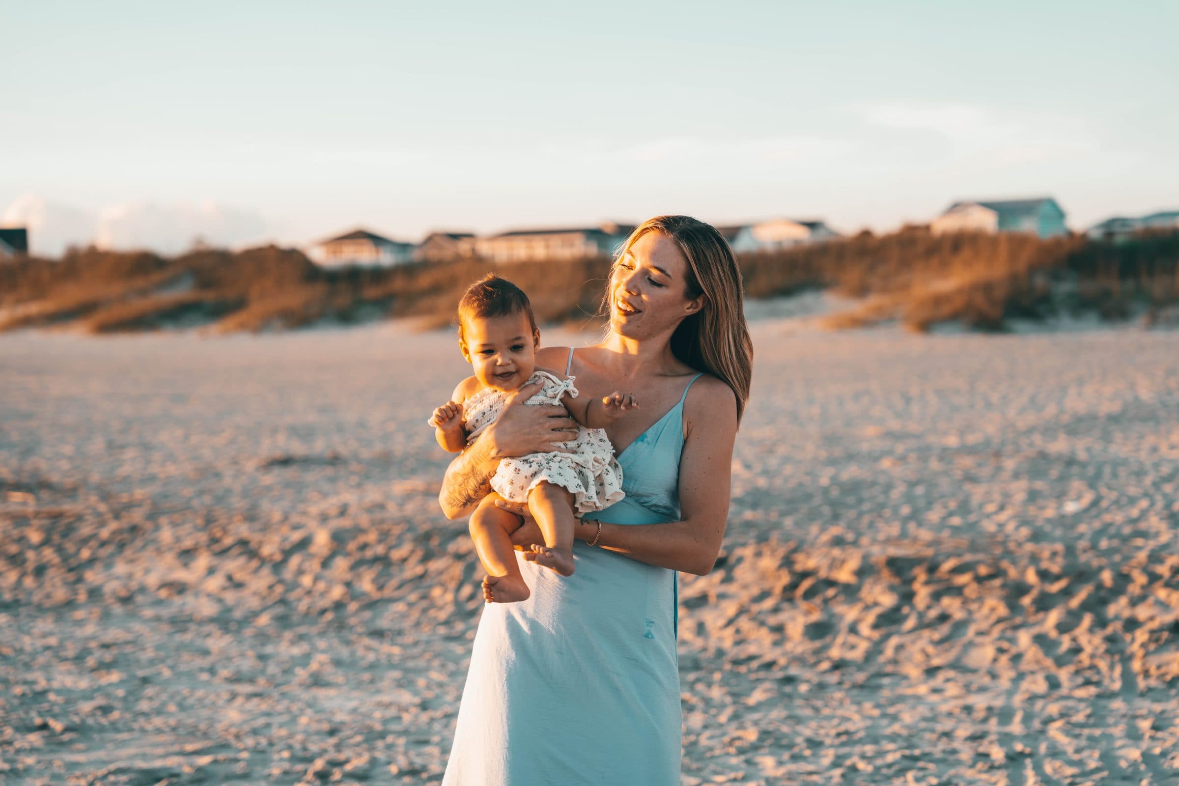 Mom holding her baby on the beach near the dunes